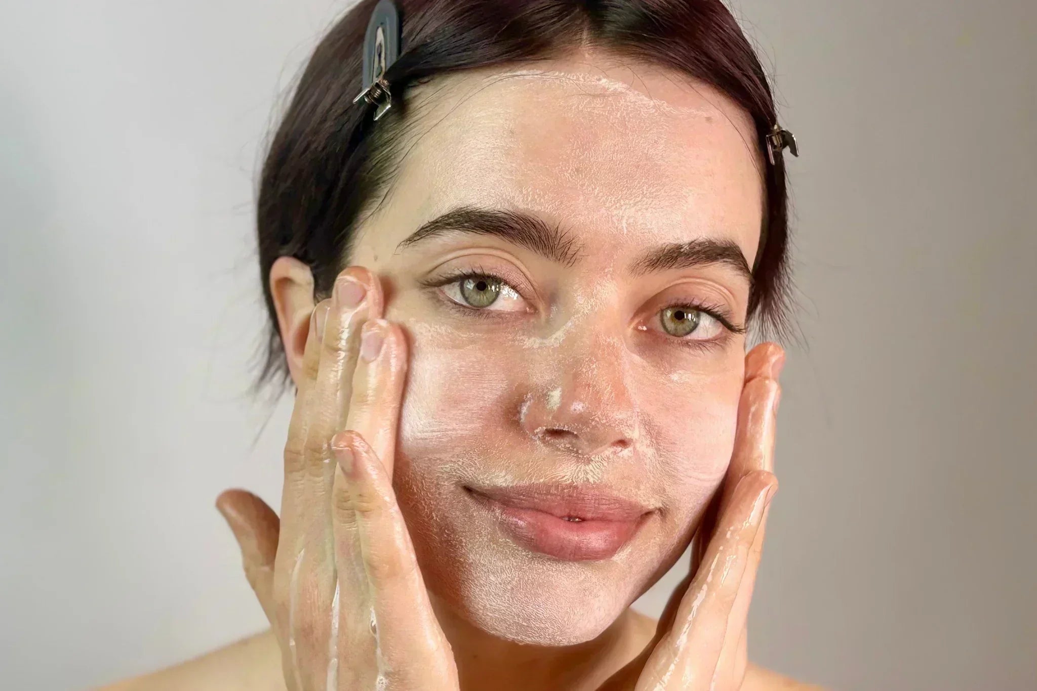 Woman cleansing her face with a gentle creamy cleanser, demonstrating how to soothe and rebalance over-exfoliated skin.