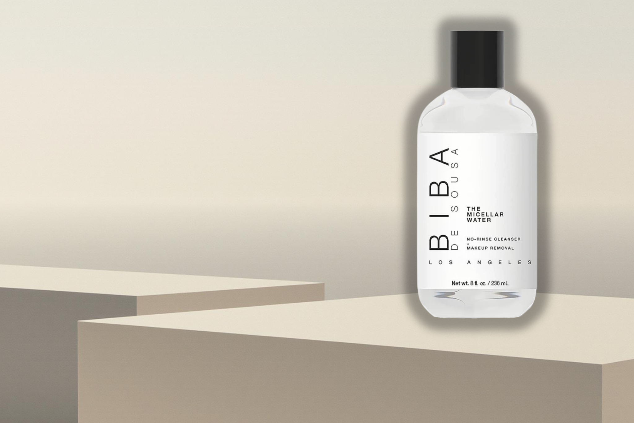 White bottle of BIBA Los Angeles The Micellar Water with black cap displayed on neutral beige pedestal blocks against a soft gradient background. Minimalist white label with vertical “BIBA” text. Clean, modern, studio-style product presentation.