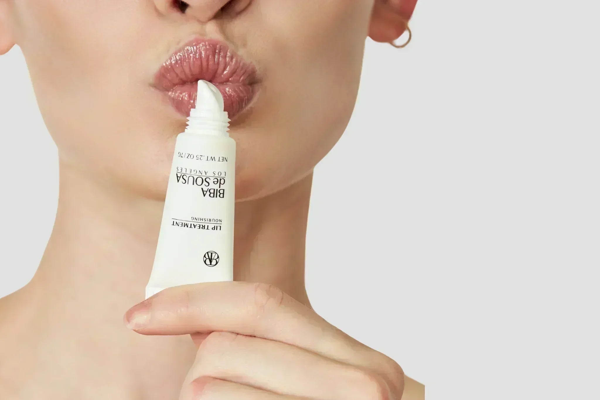 Woman applying Biba Los Angeles lip treatment balm to moisturize and protect lips