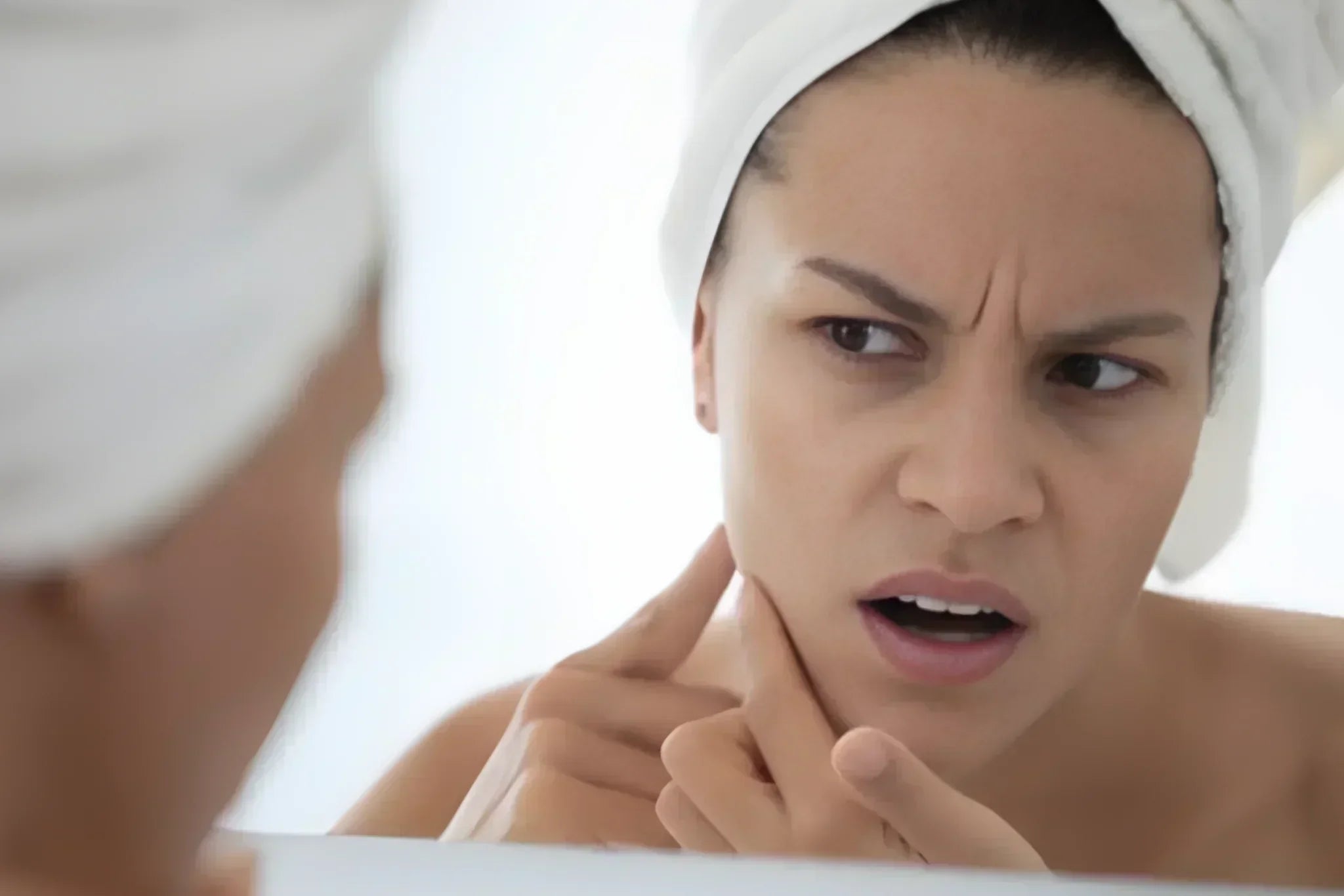 Woman anxiously examining skin in mirror