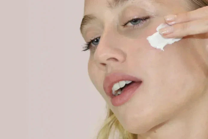 Woman applying moisturizer to her face as part of a daily skincare routine to support hydration and skin barrier health.