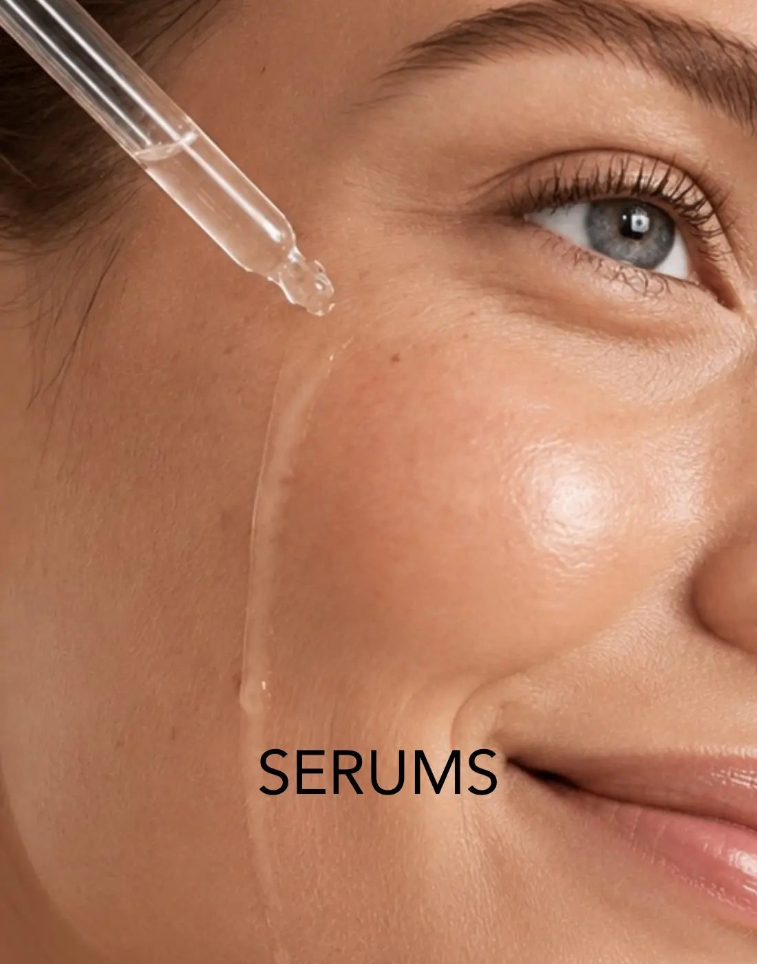 Close-up of a model applying facial serum with a glass dropper to glowing, healthy skin.