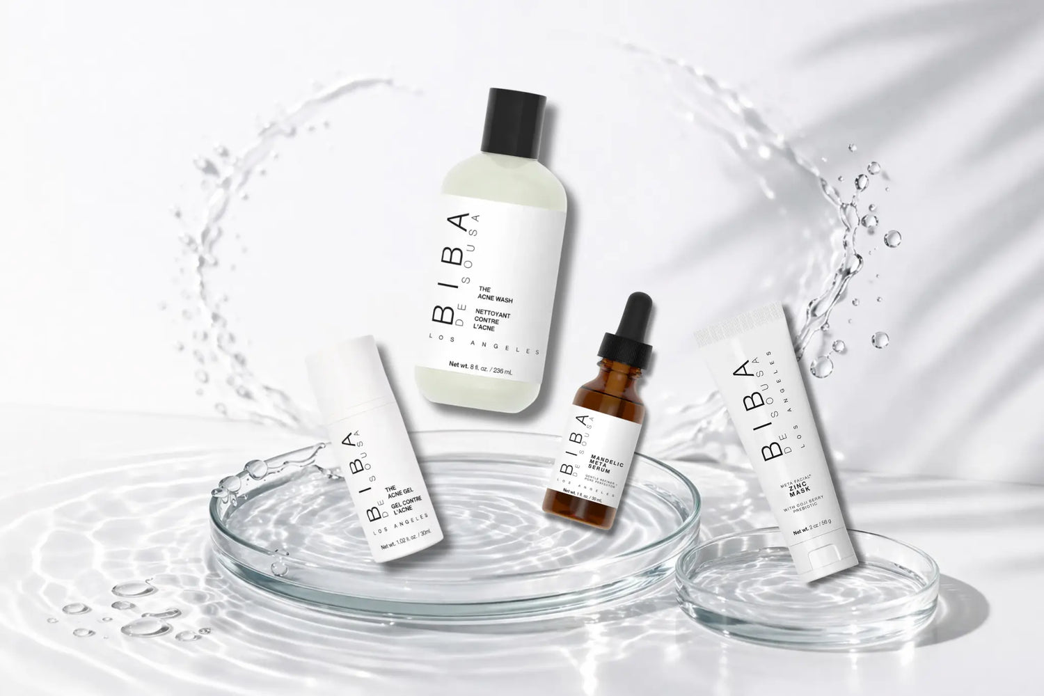 Biba de Sousa Los Angeles acne skincare products arranged on glass dishes with water ripples, including Acne Wash, Acne Gel, Mandelic Serum, and Zinc Mask on a clean white background
