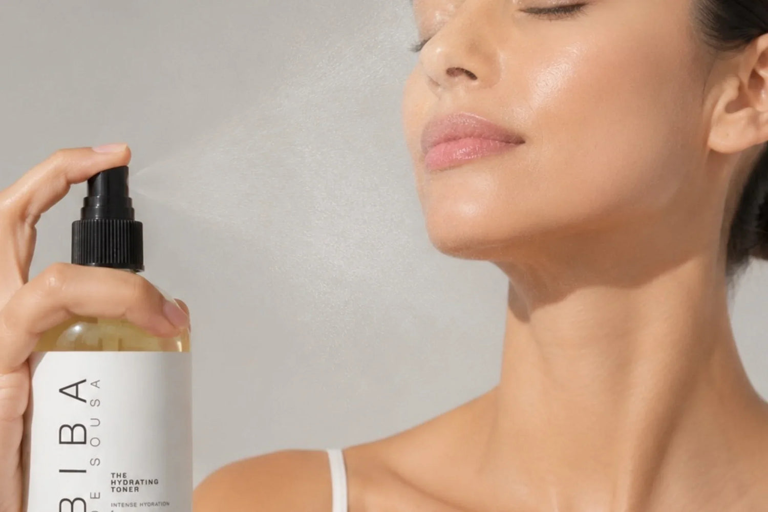 Woman misting her skin with Biba Los Angeles Hydrating Toner to replenish hydration, support the skin barrier, and help reduce transepidermal water loss (TEWL).