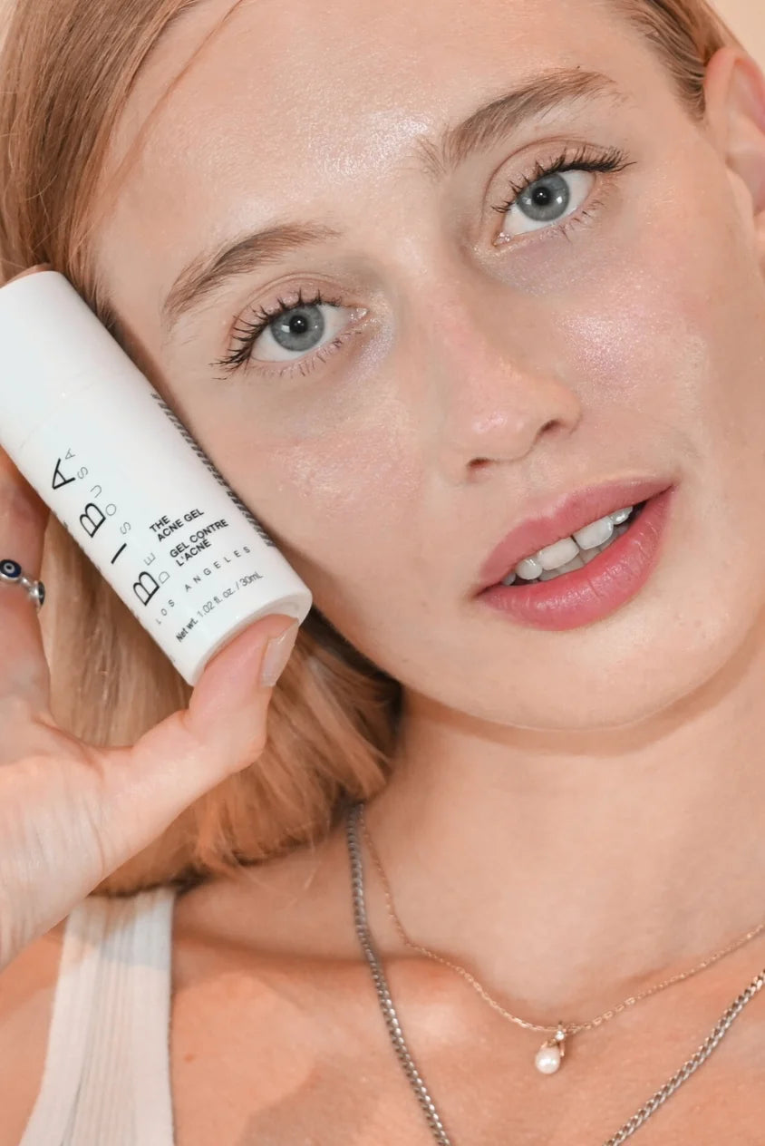 Close-up of a model holding Biba de Sousa Los Angeles The Acne Gel beside the face, showing clear, balanced skin and the product’s lightweight acne treatment format.
