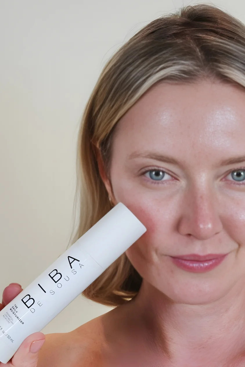 Woman holding Biba de Sousa Daily Moisturizer next to her face, showing hydrated, natural skin with a lightweight, non-greasy moisturizer suitable for acne-prone and sensitive skin.