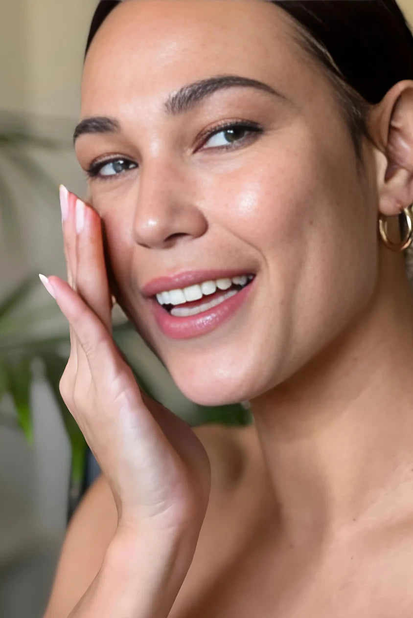 Close-up of woman with soft, hydrated skin and a natural glow, gently touching her cheek to highlight a smooth, comfortable, and well-moisturized complexion.
