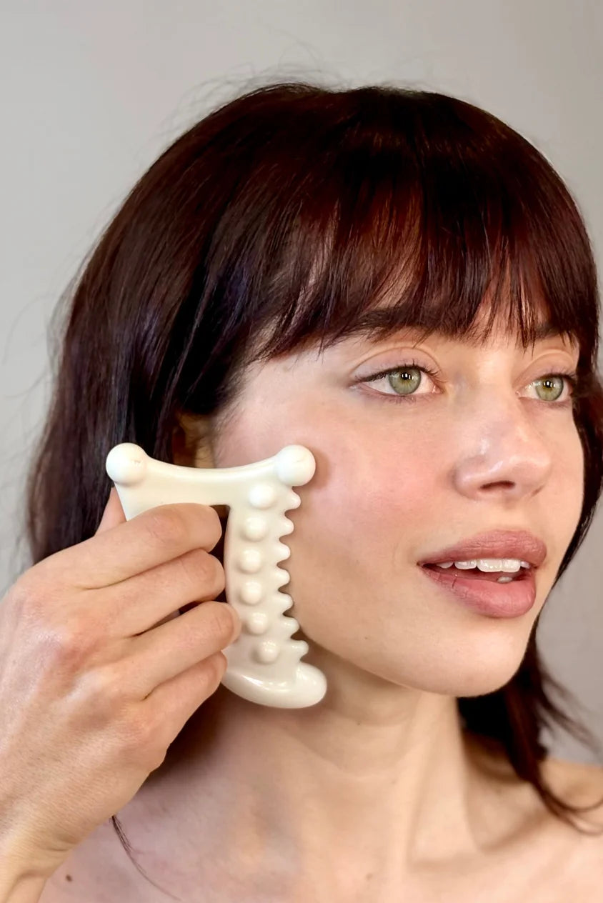 Woman using Biba de Sousa Meta Facial Fascia Tool on cheek for fascia release and facial sculpting
