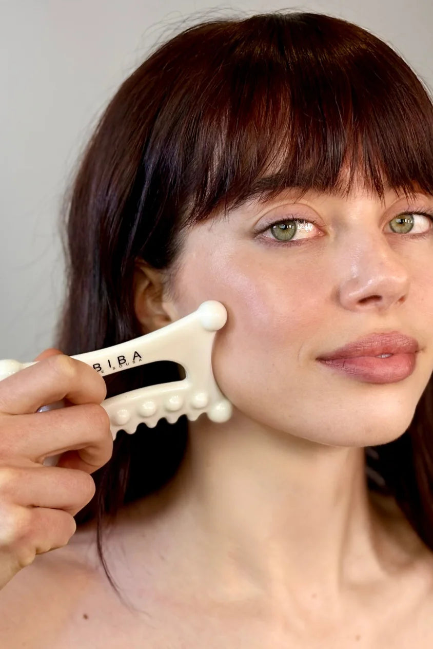Woman using Biba de Sousa Meta Facial Fascia Tool on cheek for fascia release and facial sculpting