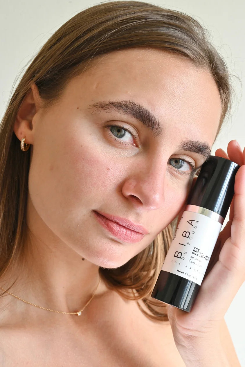 Model holding Retinol Meta Concentrate serum by Biba Los Angeles next to face