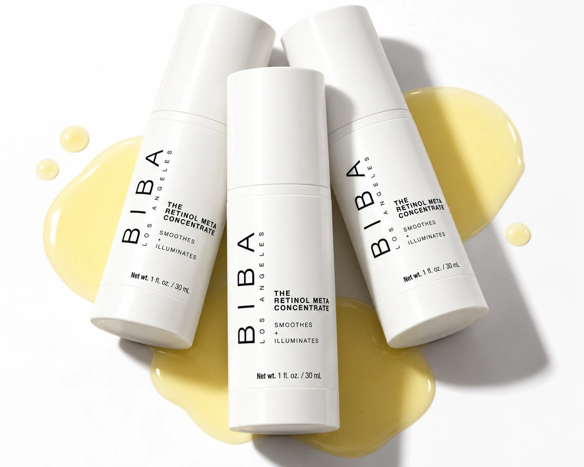 Three white BIBA Los Angeles Retinol Meta Concentrate bottles arranged over pale yellow serum on a white background.
