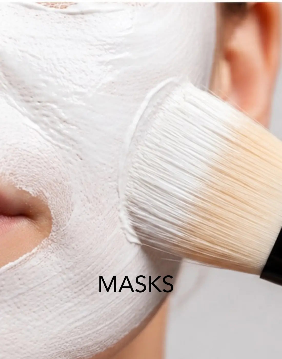 Close-up of a model applying BIBA Purifying Zinc Mask with a facial brush during a skincare treatment.