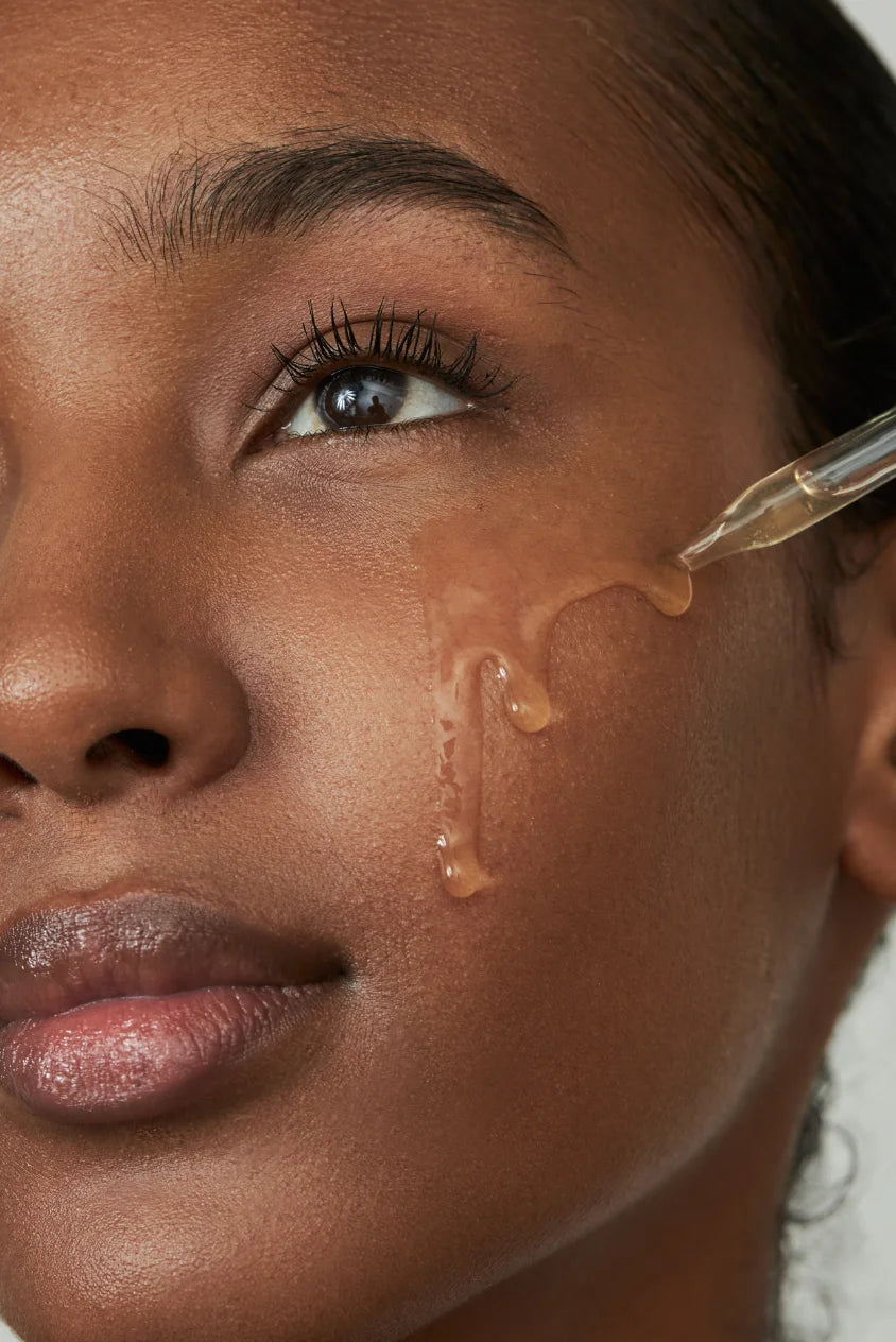 Woman applying Biba de Sousa peptide serum with dropper to cheek for hydration and skin repair